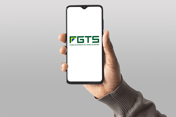 Mão segurando um celular com a logo do FGTS (Fundo de Garantia do Tempo de Serviço) na tela
